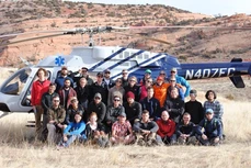 Group photo of diverse people outdoors in front of a large bus.