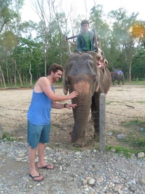 Man interacting affectionately with an elephant outdoors.