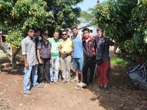 Group of eight men posing outdoors on a sunny day.