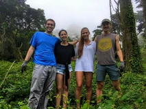 Four friends smiling outdoors in casual summer clothes.