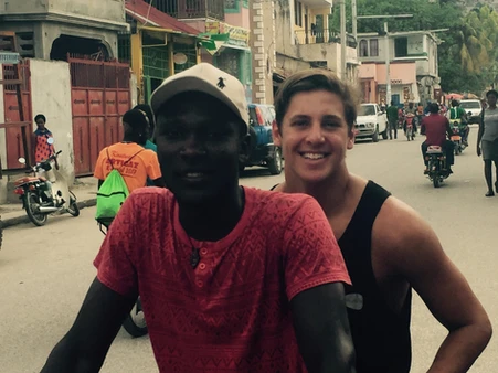 Two men smiling outdoors in a busy urban street.