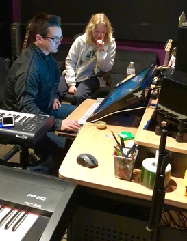 Two women working together at a computer in a studio setup.