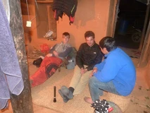 Three young men sitting and chatting indoors on a carpet.