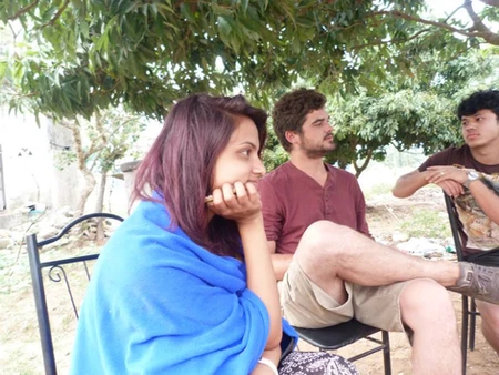 Two people sitting outdoors under a tree, engaged in conversation.