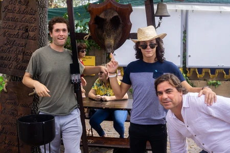 Four friends posing outdoors with a large dinosaur skull.