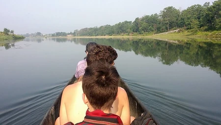 People paddling a canoe on a calm lake with trees in the background.