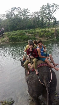 A group of people riding an elephant through a river.