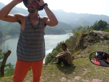 Two men relaxing near a scenic lake with mountains in the background.