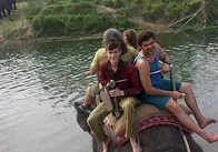 A group of people riding an elephant through a river.
